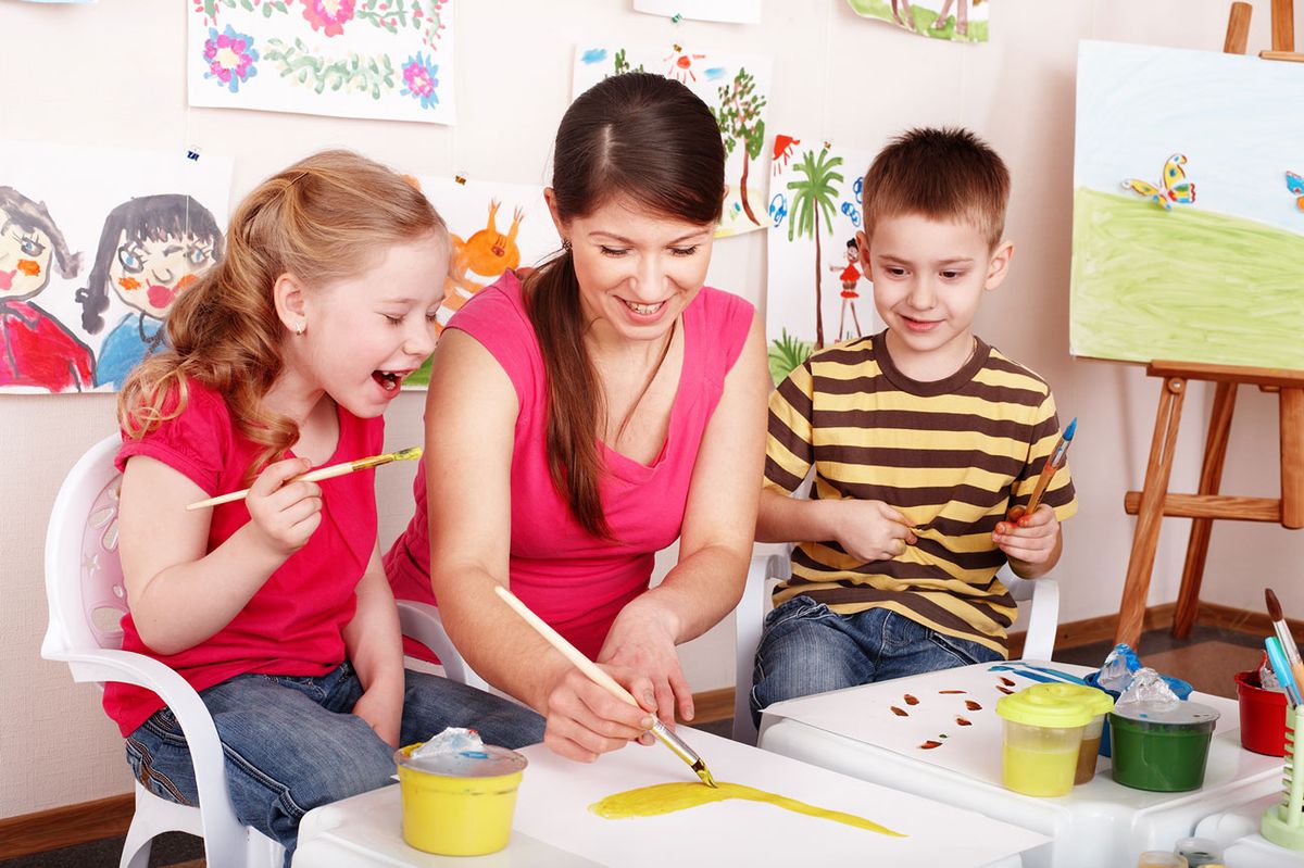 Some of the children who attend our pre-school nursery painting pictures with a staff member. 